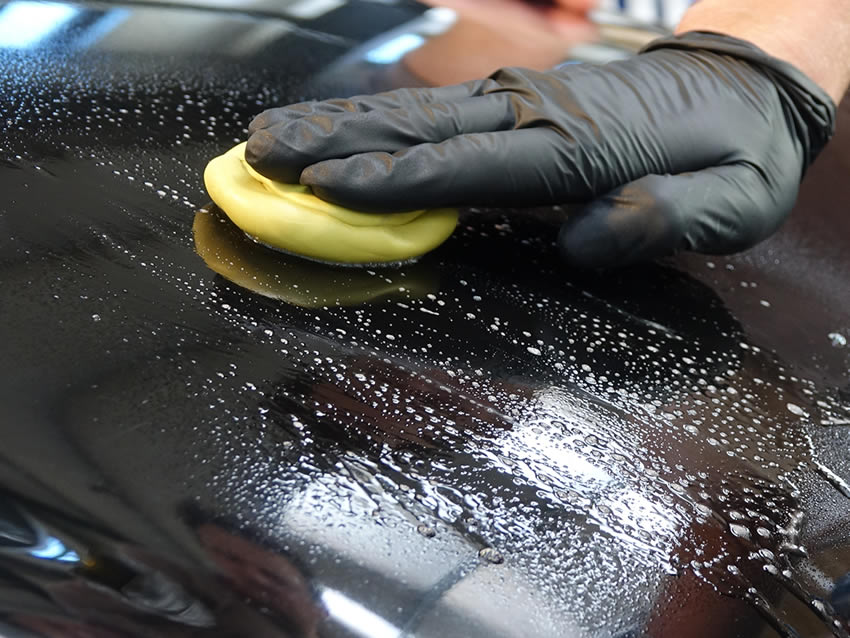 someone doing a clay bar treatment on a car